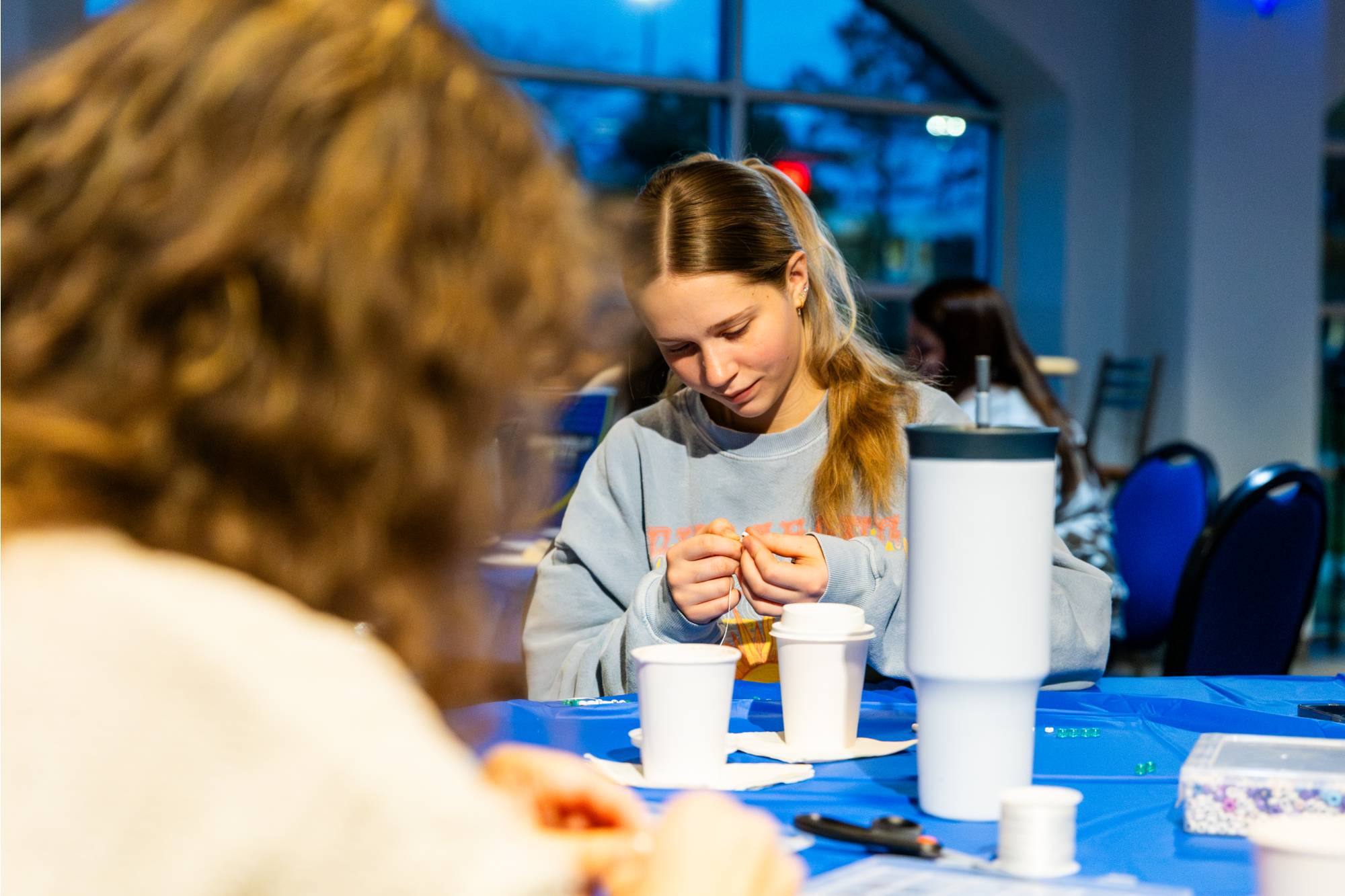 student sitting at a table working on craft